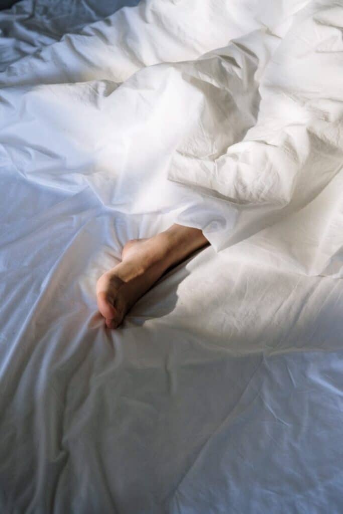A person sleeping with one foot out of the bedsheet