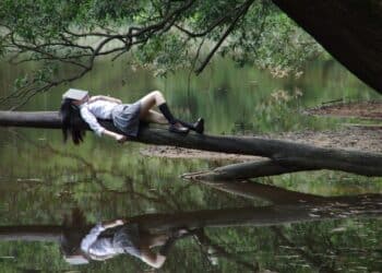 Girl napping on a tree branch on river