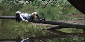 Girl napping on a tree branch on river