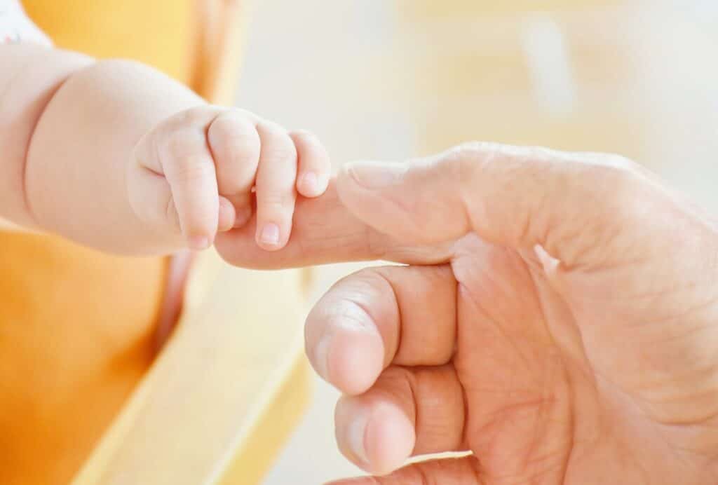 Baby holding finger of dad