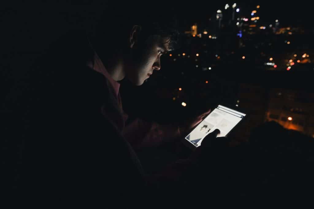Young man focusing on tablet at night