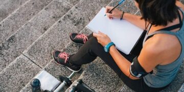 Athlete in the city who is focused on her goals scribbling on a notebook