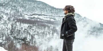Tenacious man in black jacket looking at the snow mountains