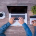 Man with blue full sleeve shirt with four hands working on his macbook