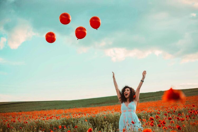 Things to remember during tough times in life-a moment of happiness of a woman in blue dress in a field of poppies