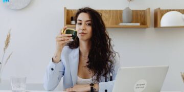 Alpha woman in blue coat drinking coffee on her office desk-alpha female traits