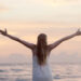 Lady stretching her arms during sunset at a beach-what it means to live your best life