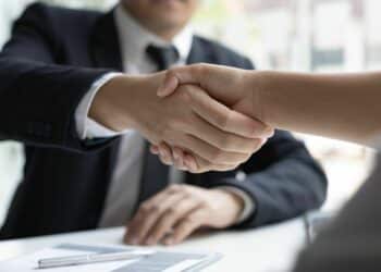 Interviewer in black suit shaking hands of the interviewee-how to hire employees effectively