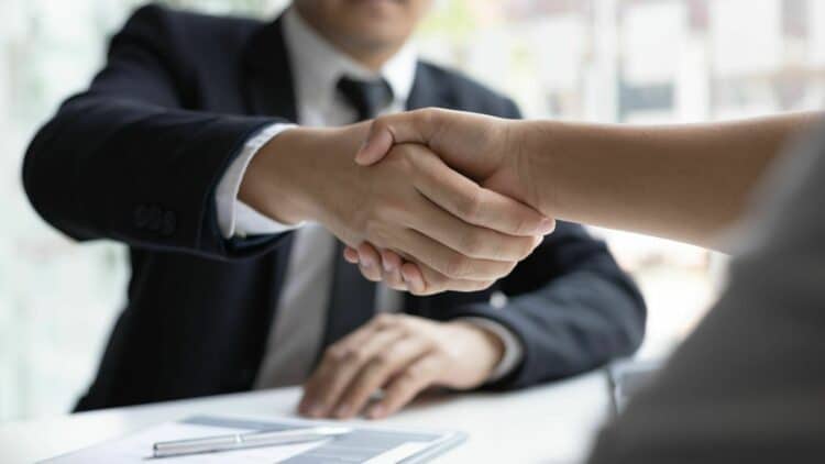 Interviewer in black suit shaking hands of the interviewee-how to hire employees effectively