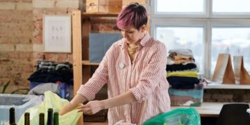 Middle-aged woman in pink shirt sorting out wastes for recycling-zero waste lifestyle