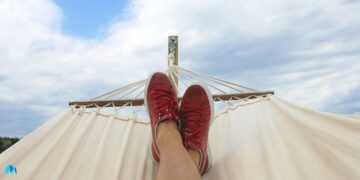 A man on hammock with a pair of red and white low top sneakers-five ways to turn being lazy into an advantage