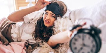 Dark haired beautiful young brunette wake up in her bed and reaching out to the alarm clock-reasons why lazy people are more likely to be successful