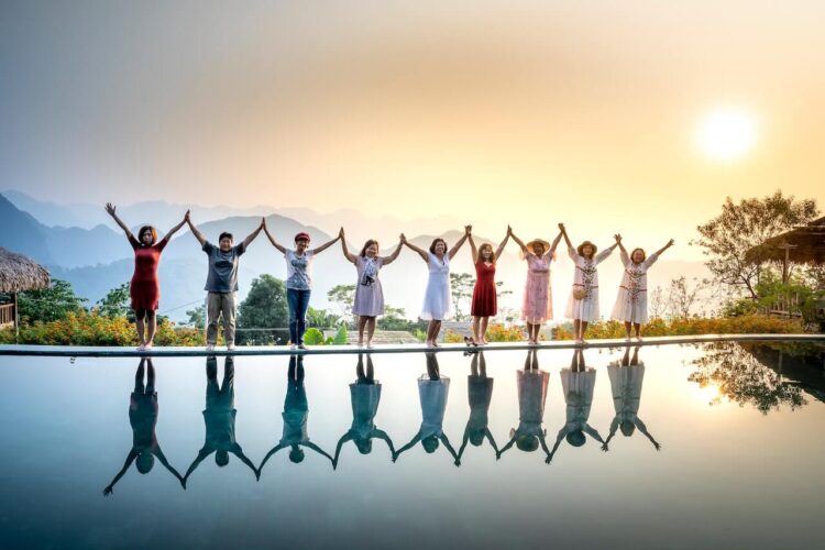 Ground of people in casual dress with raised hands in joy in front of a waterbody-the abilene paradox examples