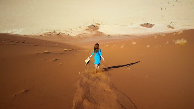 Woman in blue dress running across sand dunes-don't chase people