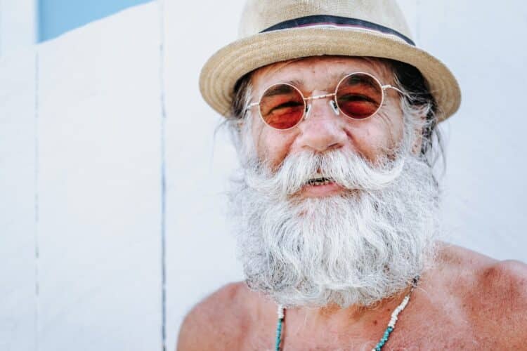 Old man in a hat and goggles smiling on camera
