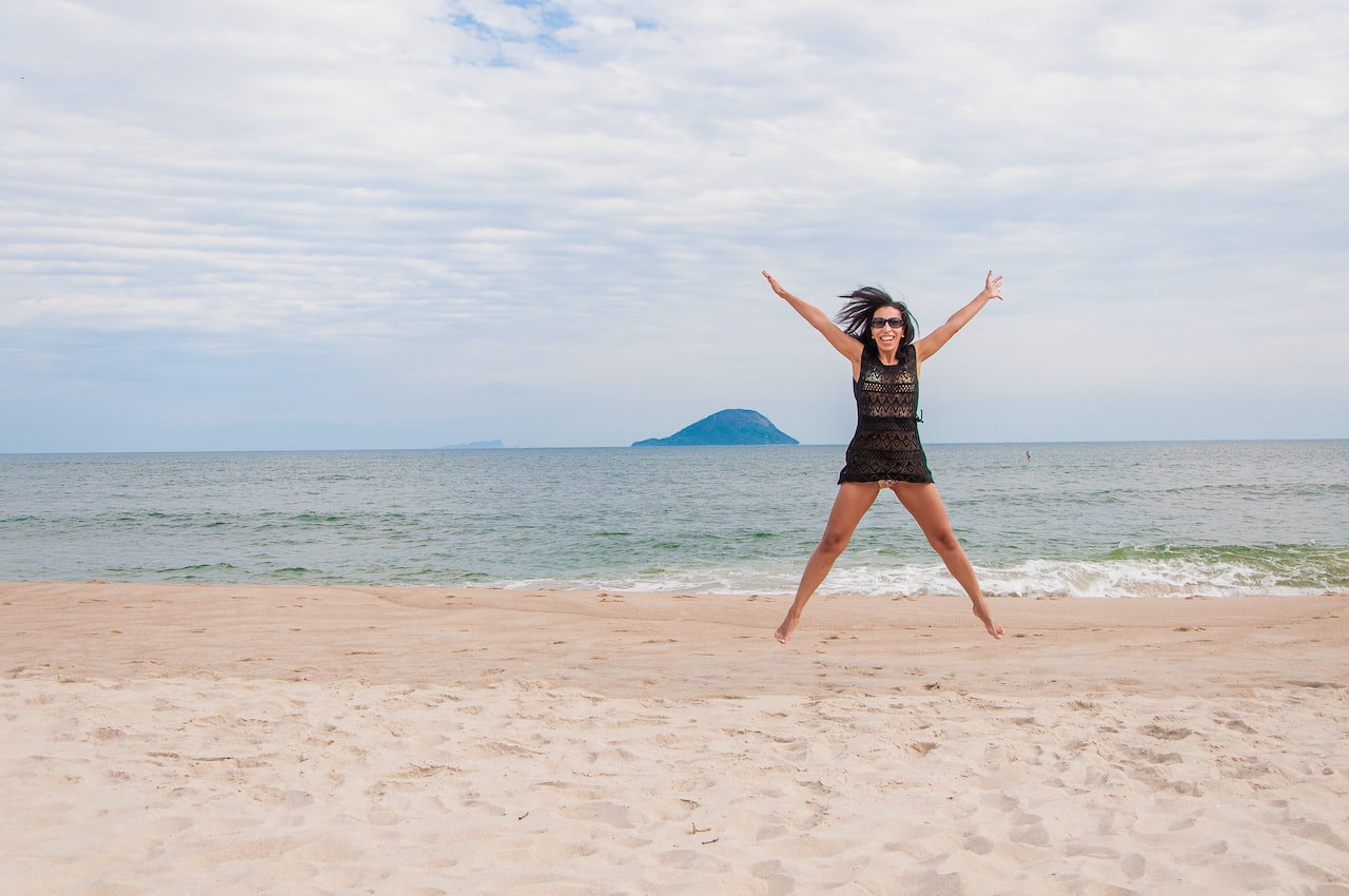 Woman in black dress standing on beach during daytime