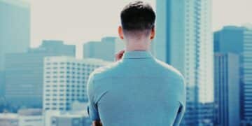 Man in blue long sleeve shirt standing in front of city buildings during daytime