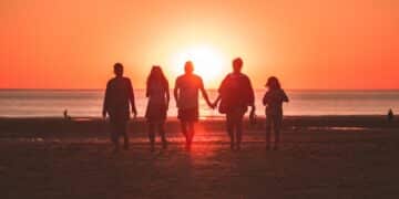 Silhouette photo of five person walking on seashore during golden hour