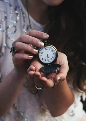 Woman holding black pocket watch at 5:30