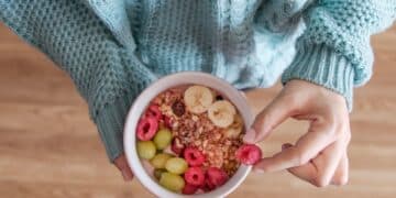 Person holding white ceramic bowl with red and yellow beans-i ate oatmeal every morning for a month-here's what happened